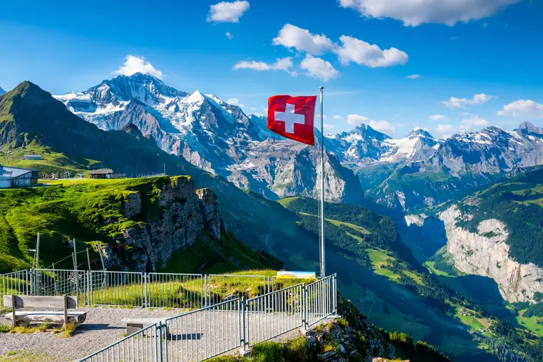 Swiss flag waving on the top of Mannlichen mountain with views of Junfrau in the background
