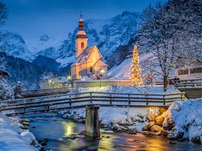 Beautiful twilight view of Sankt Sebastian pilgrimage church with decorated Christmas tree illuminated during blue hour at dusk in winter, Ramsau, Nationalpark Berchtesgadener Land, Bavaria, Germany