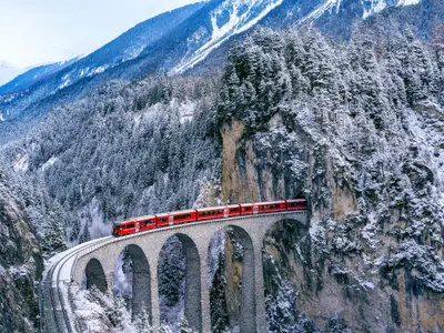 Aerial view of Train passing through famous mountain in Filisur, Switzerland. Landwasser Viaduct world heritage with train express in Swiss Alps snow winter scenery.