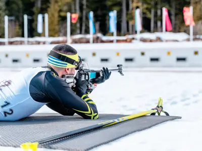 Biathlete shooting with a rifle at a shooting range at the race