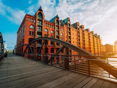 Arch bridge over canals in the Speicherstadt of Hamburg. Warm evening sun light on red brick building.