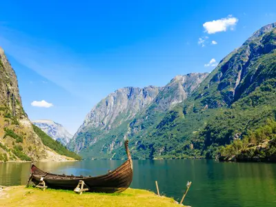 Tourism and travel. Mountains and fjord Sognefjord in Norway, Scandinavia. Old viking boat on seashore.