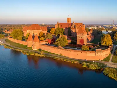 Medieval Malbork (Marienburg) Castle in Poland, main fortress of the Teutonic Knights at the Nogat river. Aerial view in fall in sunset light.