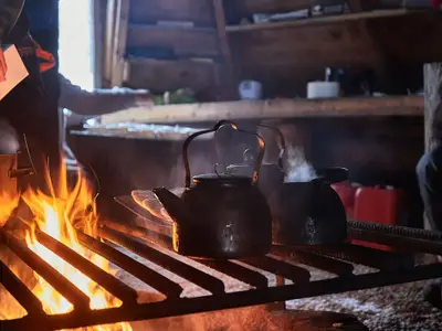 Fireplace, wood fire cooking soup and making tea in a wooden hut in the arctic