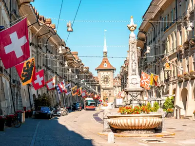 Street view on Kramgasse with fountain and clock tower in the old town of Bern city. It is a popular shopping street and medieval city centre of Bern, Switzerland