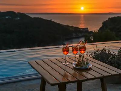 Three glasses of the famous Italian cocktail  spritz  against the background of pool, sea and sunset.