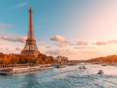 The main attraction of Paris and all of Europe is the Eiffel tower in the rays of the setting sun on the bank of Seine river with cruise tourist ships