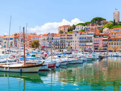 Cannes marina view on a sunny summer day, coastal landscape with moored yachts and colorful houses on a background. France