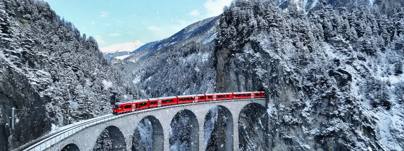 Snow falling and Train passing through famous mountain in Filisur, Switzerland. Train express in Swiss Alps snow winter scenery.