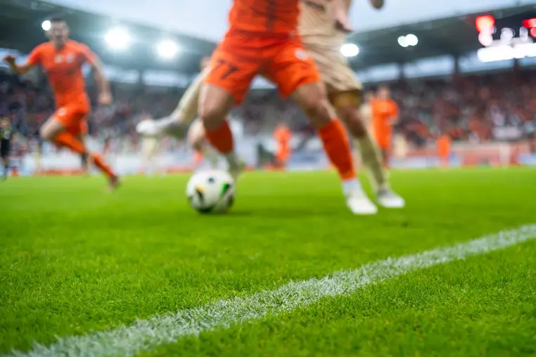 grass and sideline on the football pitch at the stadium and player's legs at the background