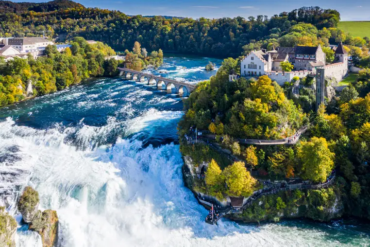 Rhine Falls or Rheinfall, Switzerland panoramic aerial view. Tourist boat in waterfall. Bridge and border between the cantons Schaffhausen and Zurich. Cliff-top Schloss Laufen castle, Laufen-Uhwiesen.