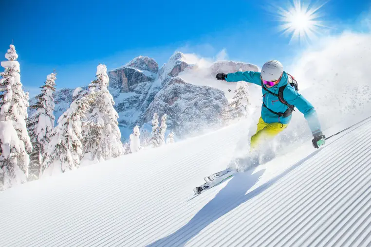 Skier skiing downhill during sunny day in high mountains